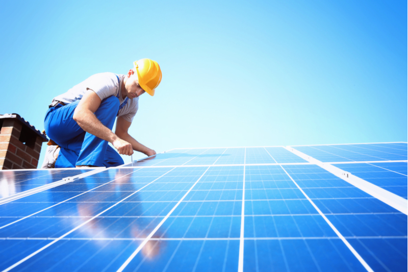 Man installing solar panels on roof